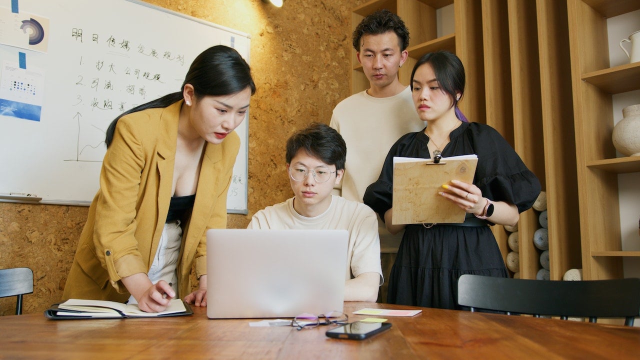 group-of-asian-coworkers-looking-at-project-in-laptop-discussing-and-planning-at-meeting-convergert-thinking