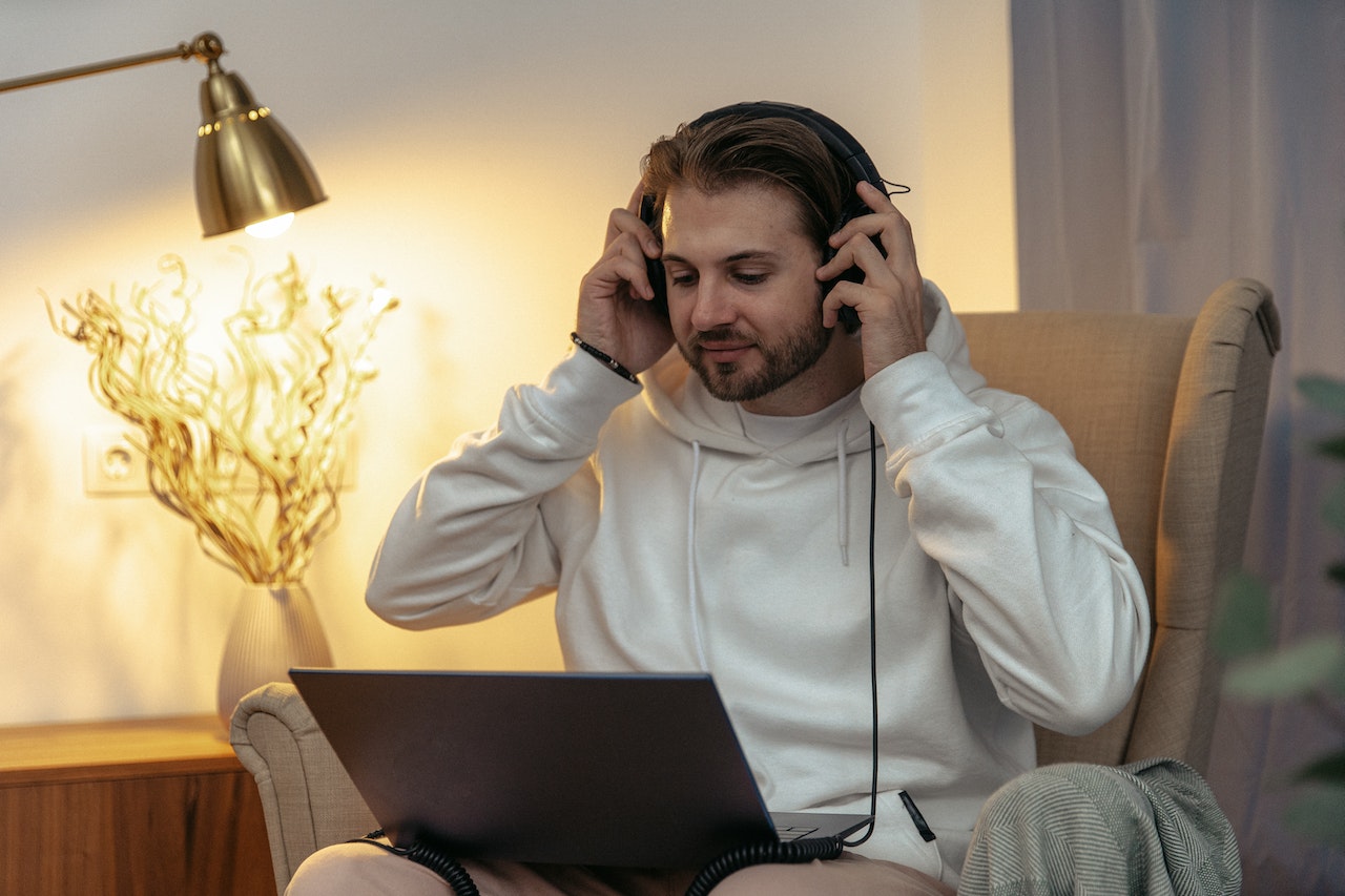 man-sitting-at-home-using-laptop-while-listening-on-headphones-business-podcasts