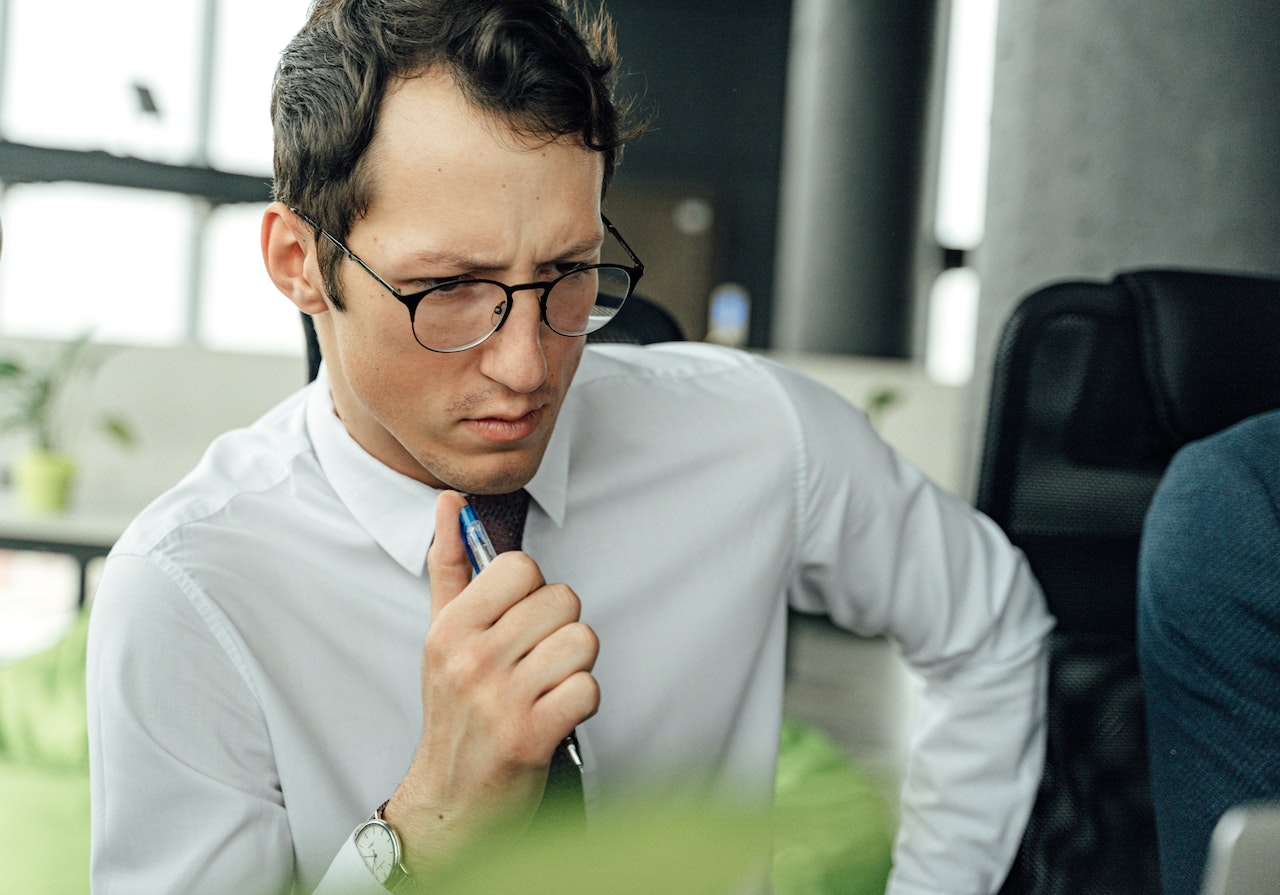 man-thinking-while-holding-pen-and-looking-at-computer-how-to-develop-critical-thinking-skills