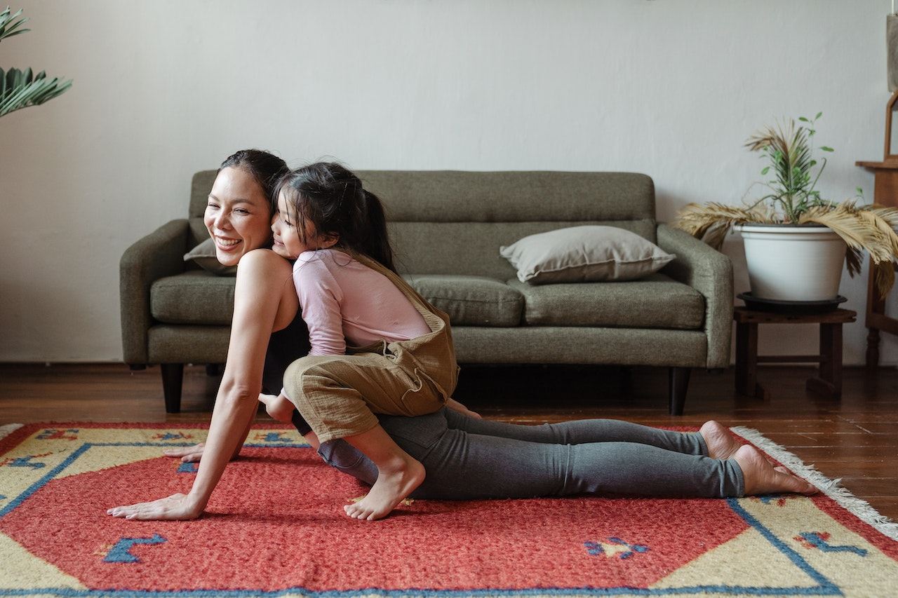 mom-and-her-toddler-daughter-stretching-on-yoga-mat-laughing-positive-parenting