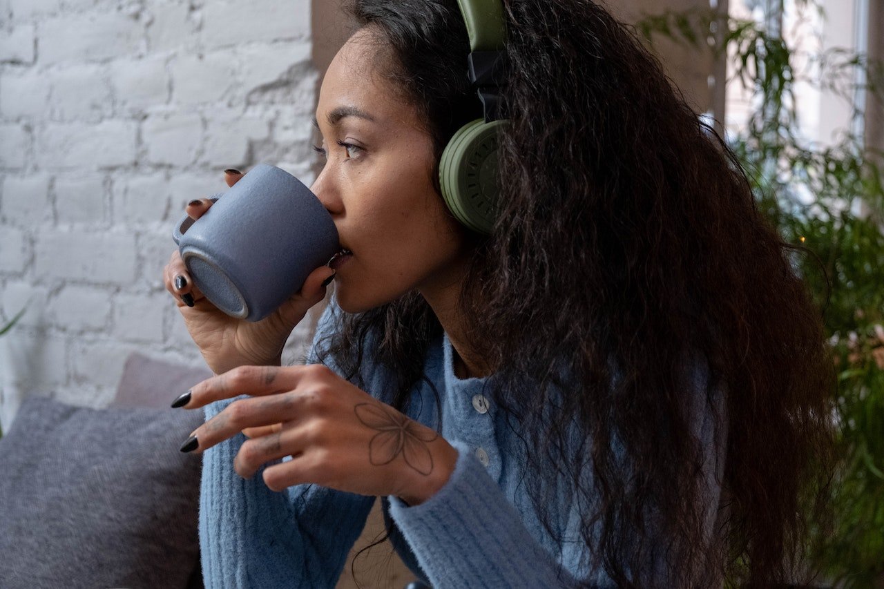 woman-listening-to-podcast-on-headphones-while-drinking-coffee-alone-best-ted-talks-about-life